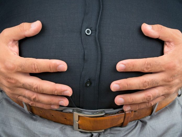An overweight man holding his stomach